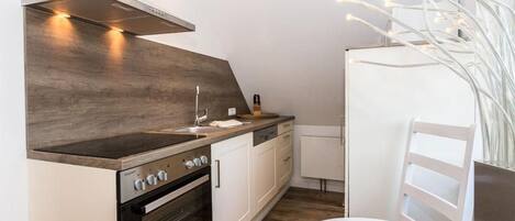 Una cocina compacta con estufa, horno y armarios blancos.