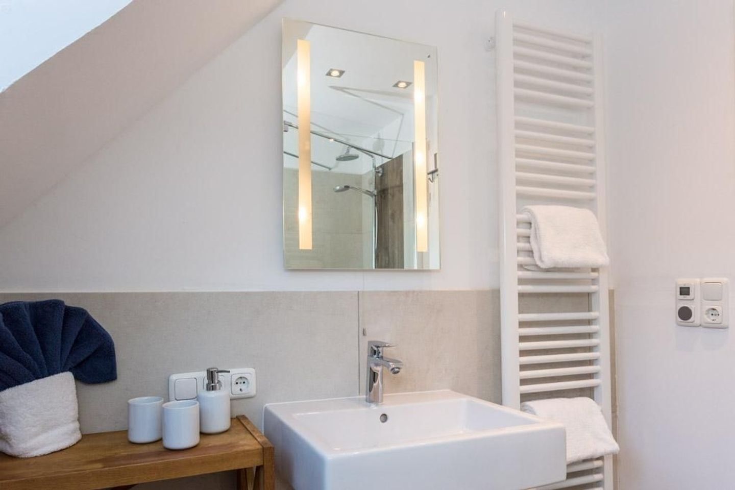 Een moderne badkamer met een wit wastafelmeubel, een spiegel en een handdoekhouder.