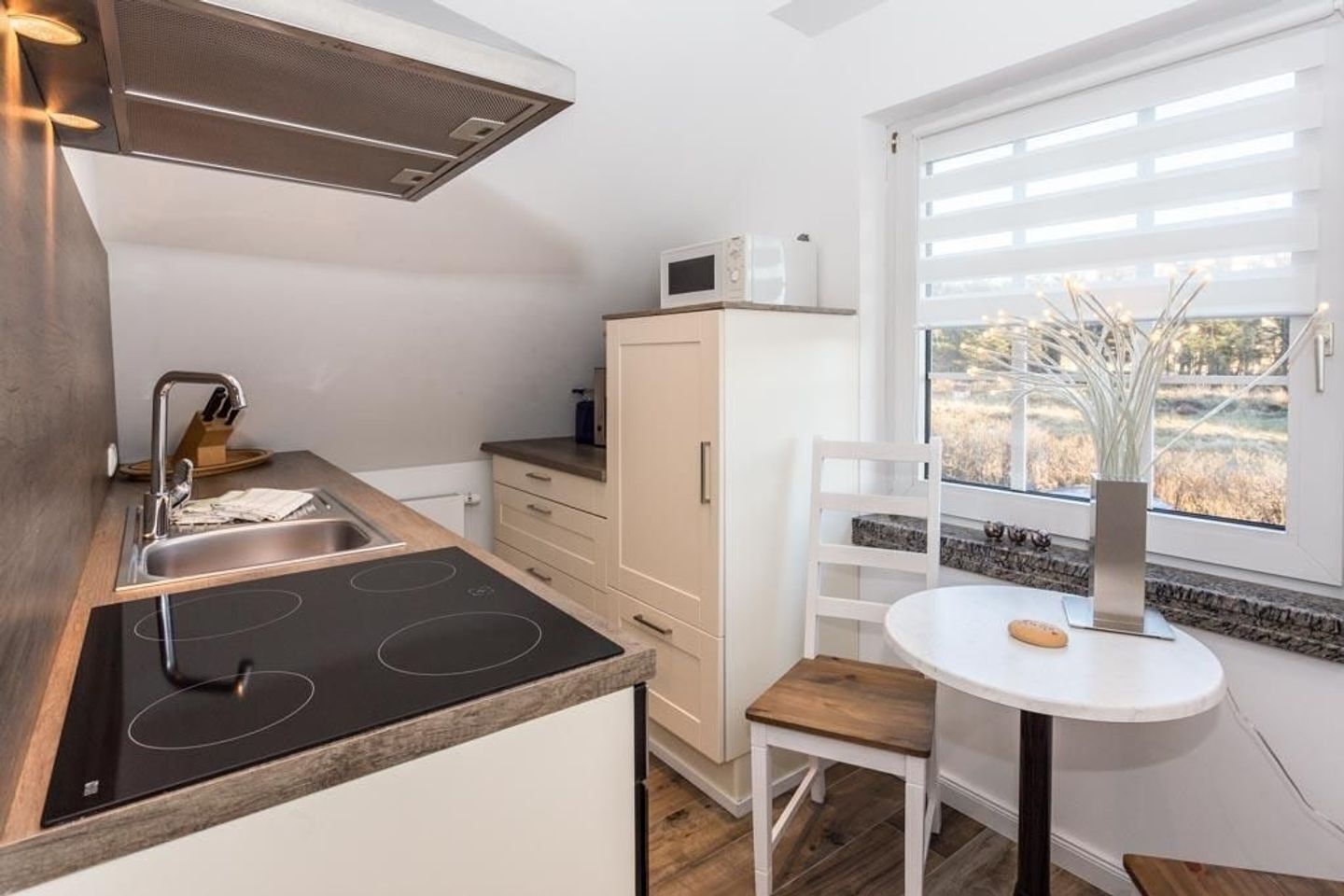 Una cocina moderna con estufa integrada, microondas y ventana con vistas al exterior.