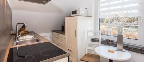 Una cocina moderna con estufa integrada, microondas y ventana con vistas al exterior.