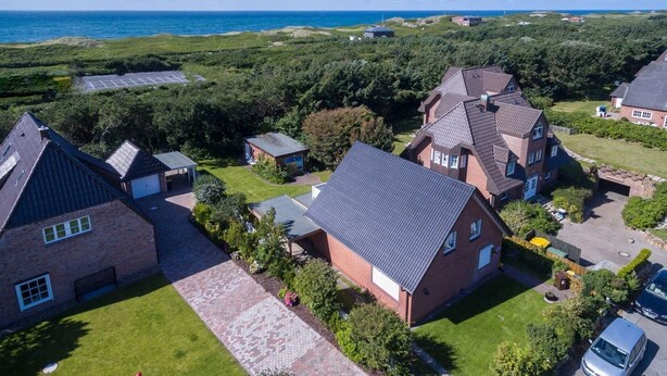 A residential area with houses, a parking lot, and a view of the sea. - Seerose Sylt - Modern 3-room apartment with dune view and balcony (Sylt)