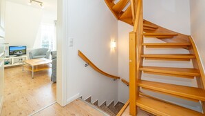 A wooden staircase in a modern apartment with a flat-screen TV in the living room. - Conwind apartment 5b - New with us! Apartment with terrace and private parking space (Sylt-Ost)