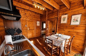L’intérieur d’une cabane en bois comprend une cuisine, un coin repas et des tableaux encadrés accrochés aux murs.
