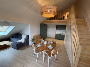 Ein modernes Interieur mit Essbereich, einer Couch, einer Treppe und einer Küche.