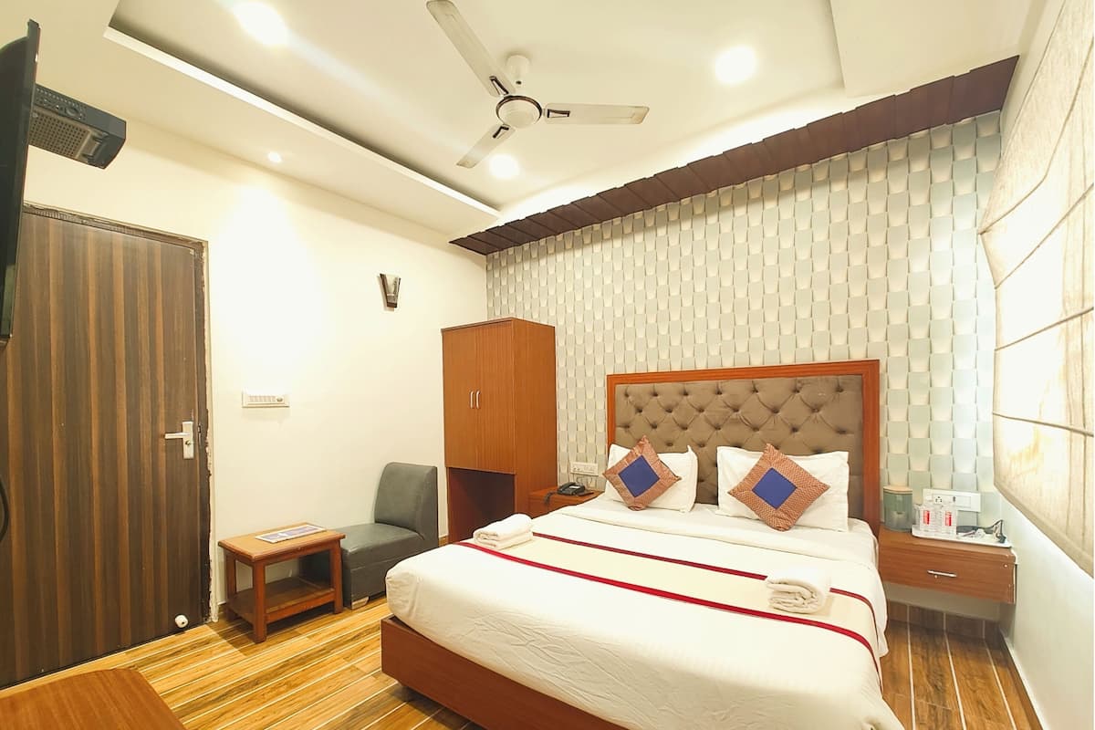A hotel room with a large bed, a wardrobe, a desk, and a ceiling fan.