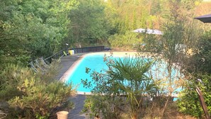 A swimming pool surrounded by dense foliage, with a wooden deck and a metal fence. - Domaine de Castillou (Luc-sur-Aude)