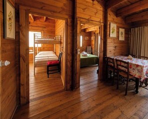Une cabane en bois avec des lits superposés, un coin repas et une cuisine.