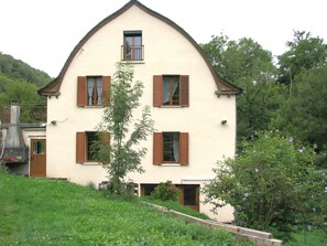 A two-story house with a steep gabled roof, multiple windows with shutters, and a small balcony. - Maison du Combayre in Estaing (Estaing)