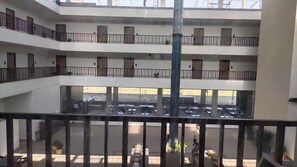 Un immeuble à plusieurs étages, doté de balcons, d’une colonne centrale et d’un espace de stationnement situé en dessous.