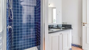 A bathroom with a blue-tiled shower, a white sink, and a mirror above it. - Villa Chez Piè: Panoramic Views, Pool & Concierge (Massa Lubrense)