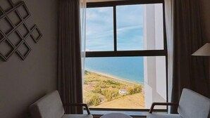 Une pièce avec deux canapés placés face à une grande fenêtre donnant sur un paysage côtier.