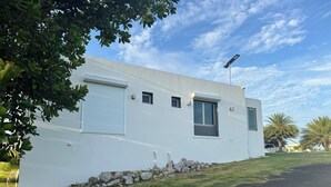 A modern white building with a sloped roof, a small window, and a solar panel. - Blue Skies Large Studio Apartment (Aguadilla)