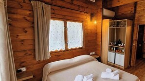 Une pièce de cabane en bois comprenant un lit, des rideaux, une armoire et une fenêtre.