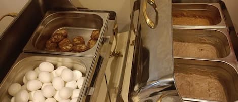 A buffet setup with various food items including eggs, meat, and a bread station.