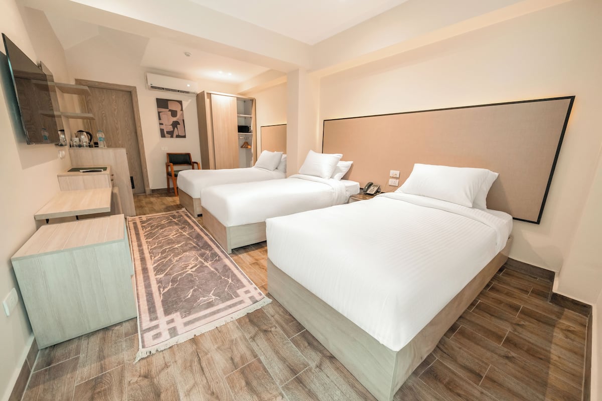 A hotel room with two beds, a desk, a chair, a mirror, and a wardrobe.