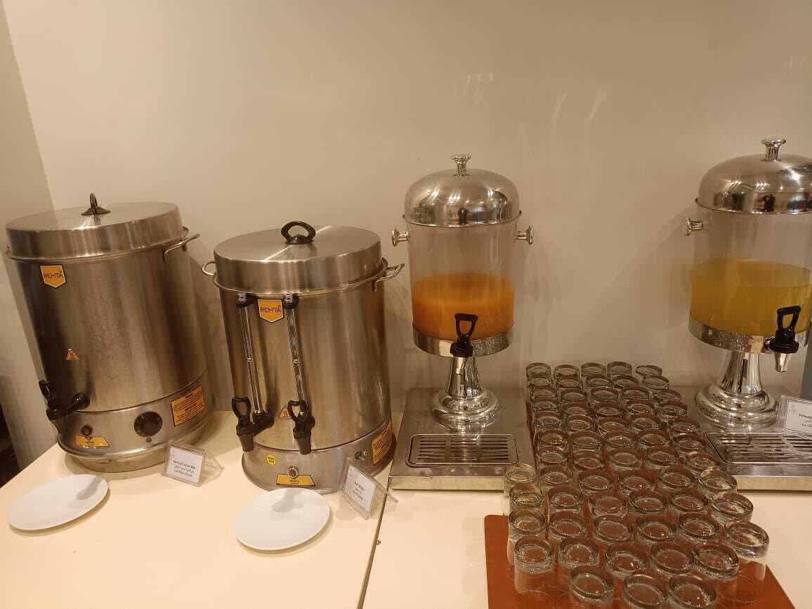 Un espace dédié au café, équipé de trois distributeurs de café, d’un plateau rempli de gobelets jetables et d’un panneau indiquant le type de café.