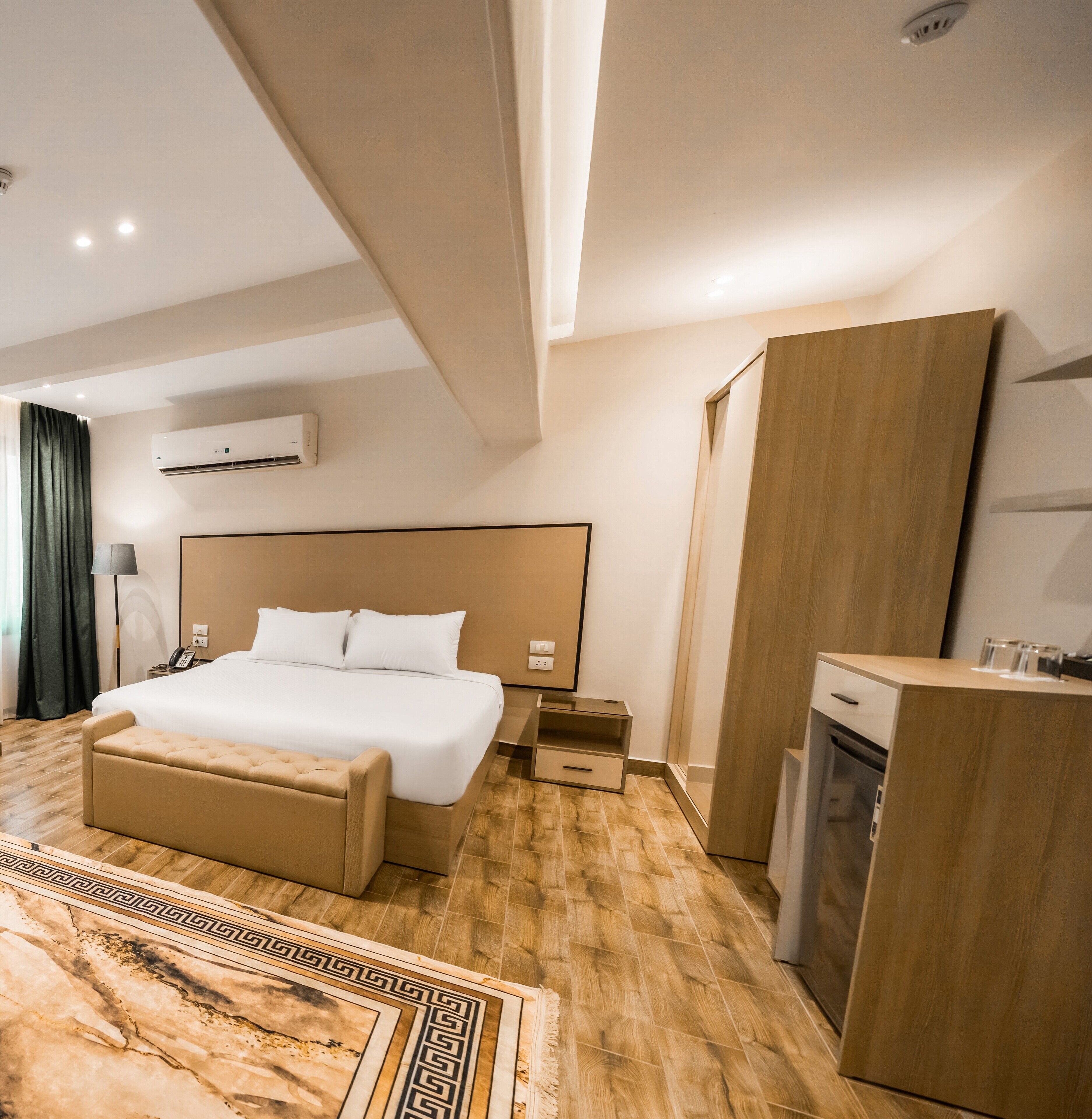 Una habitación de hotel moderna con una cama grande, una mesita de noche, un escritorio y un horno empotrado.