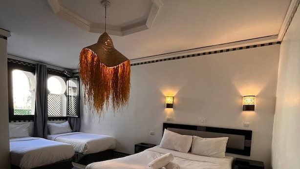 A bedroom with a large bed, two smaller beds, a hanging light fixture, and two wall-mounted lights. - Hôtel Islane Médina (Marrakech)