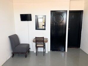 A room with a chair, a table, a flat-screen TV, a mirror, and a black door. - Hôtel Islane Médina (Marrakech)