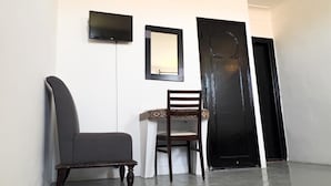A hallway with a dark chair, a white chair, a framed mirror, and a black door. - Hôtel Islane Médina (Marrakech)