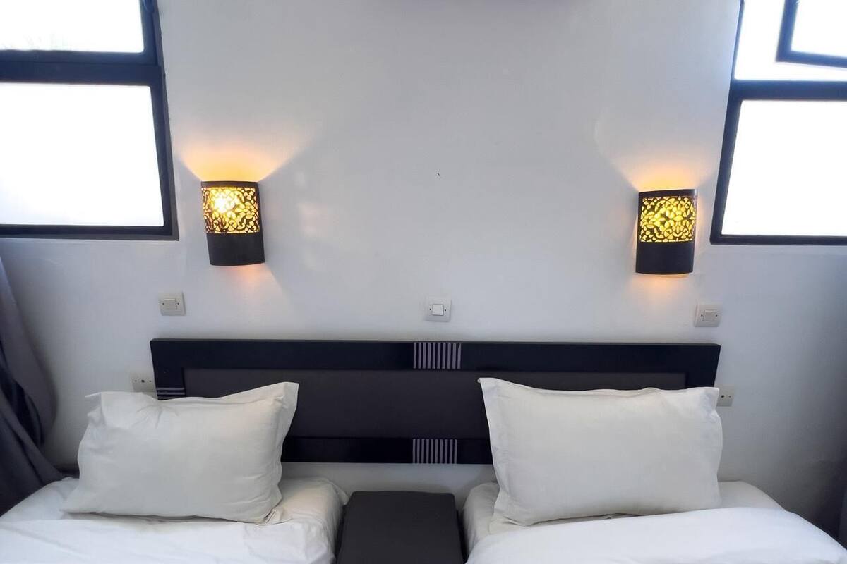Ein Hotelzimmer mit einem Bett, zwei Nachttischen und zwei Wandlampen.