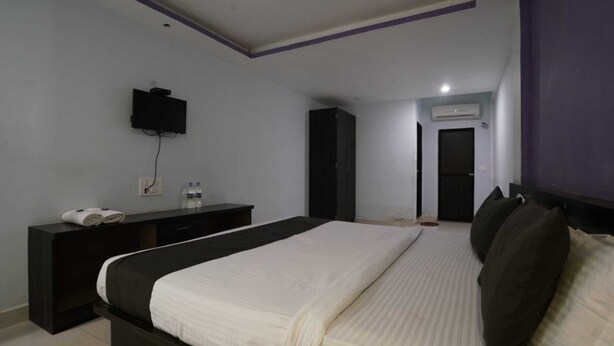 Un dormitorio con cama, televisor montado en la pared, armario y aire acondicionado.