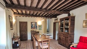 A dining area with a wooden table and chairs, a red sofa, and a cabinet with glassware. - Wonderful private villa for 6 people with WIFI, patio, pets allowed and panoramic view (Castiglione Della Pescaia)