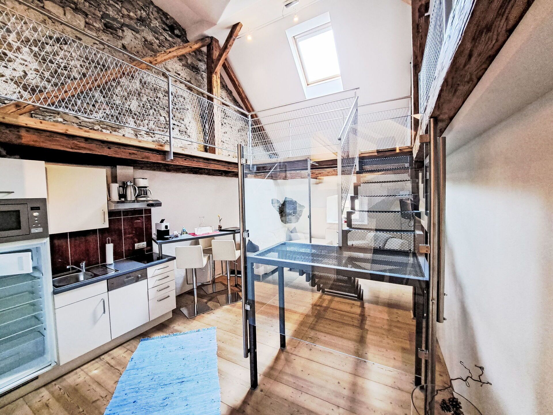 Une cuisine moderne avec un coin repas, un escalier et une vue sur l’extérieur.