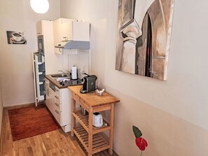 Une cuisine compacte équipée d’un réfrigérateur, d’un four et d’une machine à café posée sur le plan de travail.