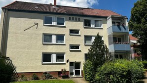 Un immeuble à plusieurs étages, à la façade beige, doté de nombreuses fenêtres et surmonté d’un toit recouvert de tuiles rouges.