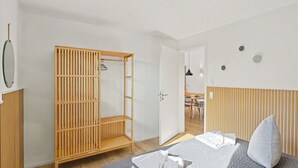 Ein Schlafzimmer mit einem Bett, einem Holzschrank, einem Spiegel und einer Tür zum Essbereich.