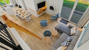Ein modernes Wohnzimmer mit Sofa, Couchtisch, Fernseher und Essbereich.