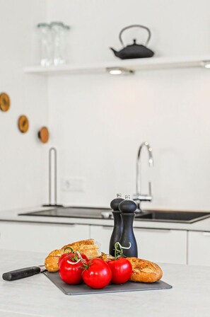 A kitchen with a cutting board, tomatoes, a knife, and a black pepper grinder. - Stunning private villa for 8 people with pool, hot tub, WIFI, TV and terrace (Diepholz)