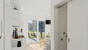 A modern kitchen with white cabinetry, a built-in stove, and a dining area with a table and chairs. - Cosy apartment for 4 guests with WIFI, TV, terrace and pets allowed (Diepholz)