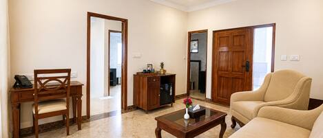 A living room with a sofa, a wooden coffee table, a wooden desk with a telephone, and a cabinet.