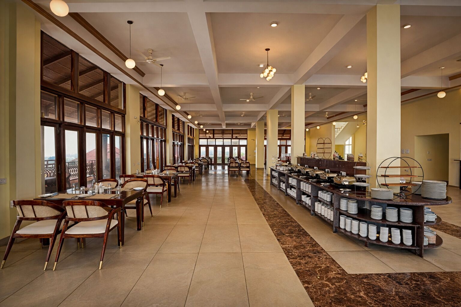 Un vaste espace de restauration dans l’hôtel, avec de longues tables, des chaises et un buffet.