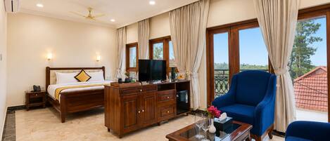 A hotel room with a bed, a television, a desk with a computer, a chair, and a balcony with a view.
