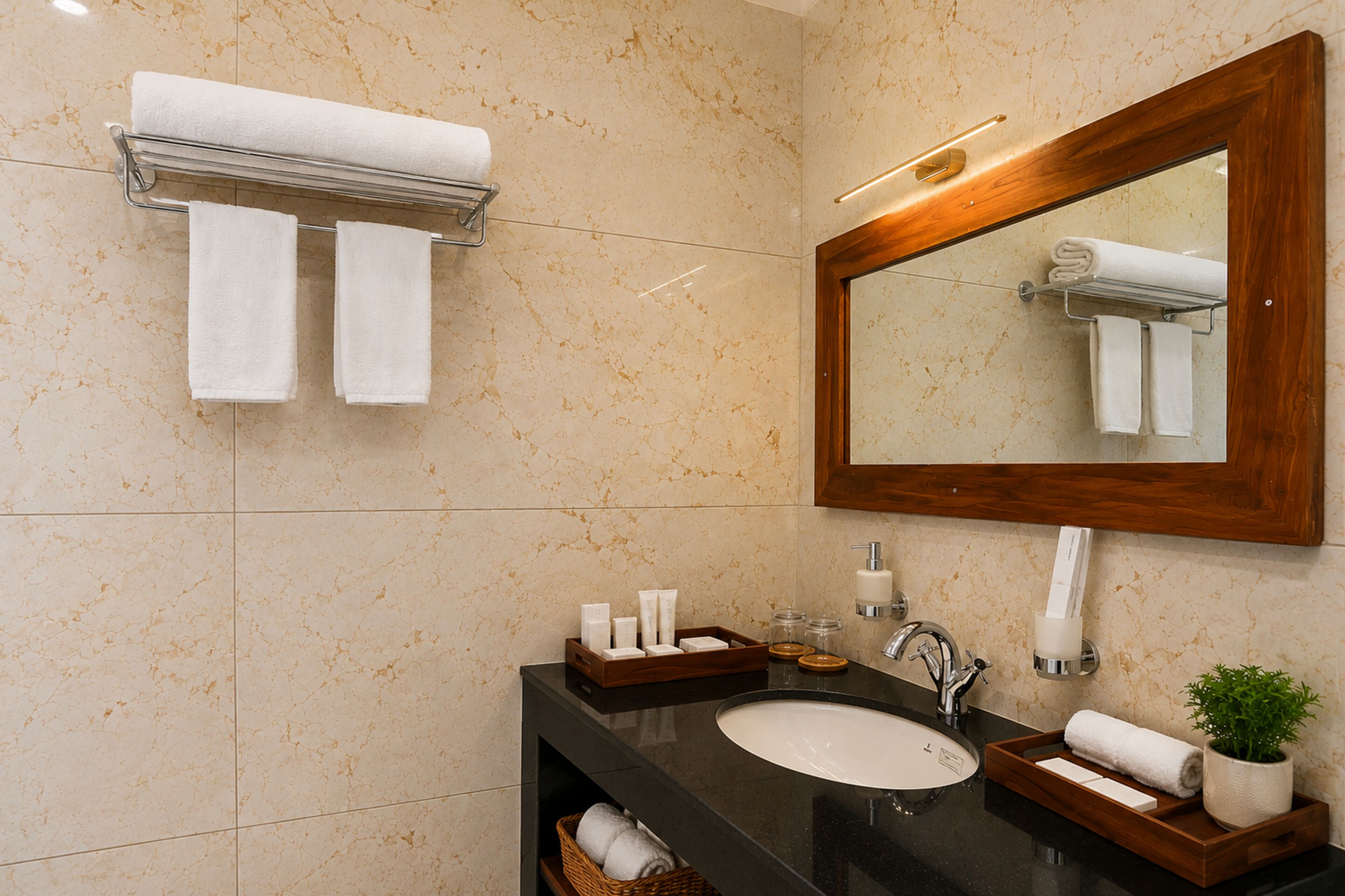 Une salle de bain avec un mur en marbre, un miroir encadré en bois, un lavabo noir et un porte-serviettes.