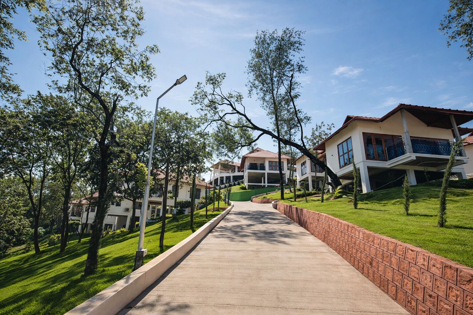 A residential area with a paved walkway, houses with balconies, and trees.