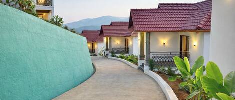 A pathway leading to a row of houses with red tiled roofs, white walls, and outdoor lighting.