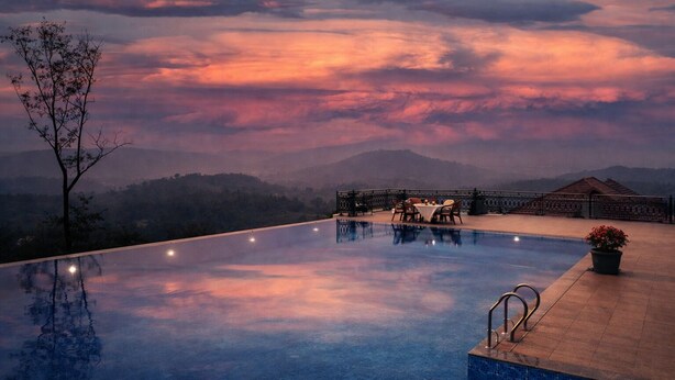 Ein Infinity-Pool mit Essbereich und Blick auf die Berge im Sonnenuntergang.