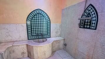 Une salle de bain avec un sol carrelé, un lavabo et un espace douche.