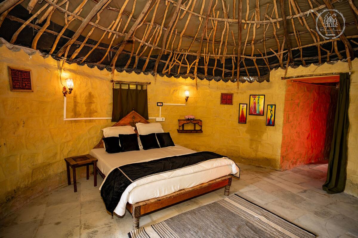 Una habitación tradicional con cama, una mesita, luces en la pared y estructura de techo de madera.