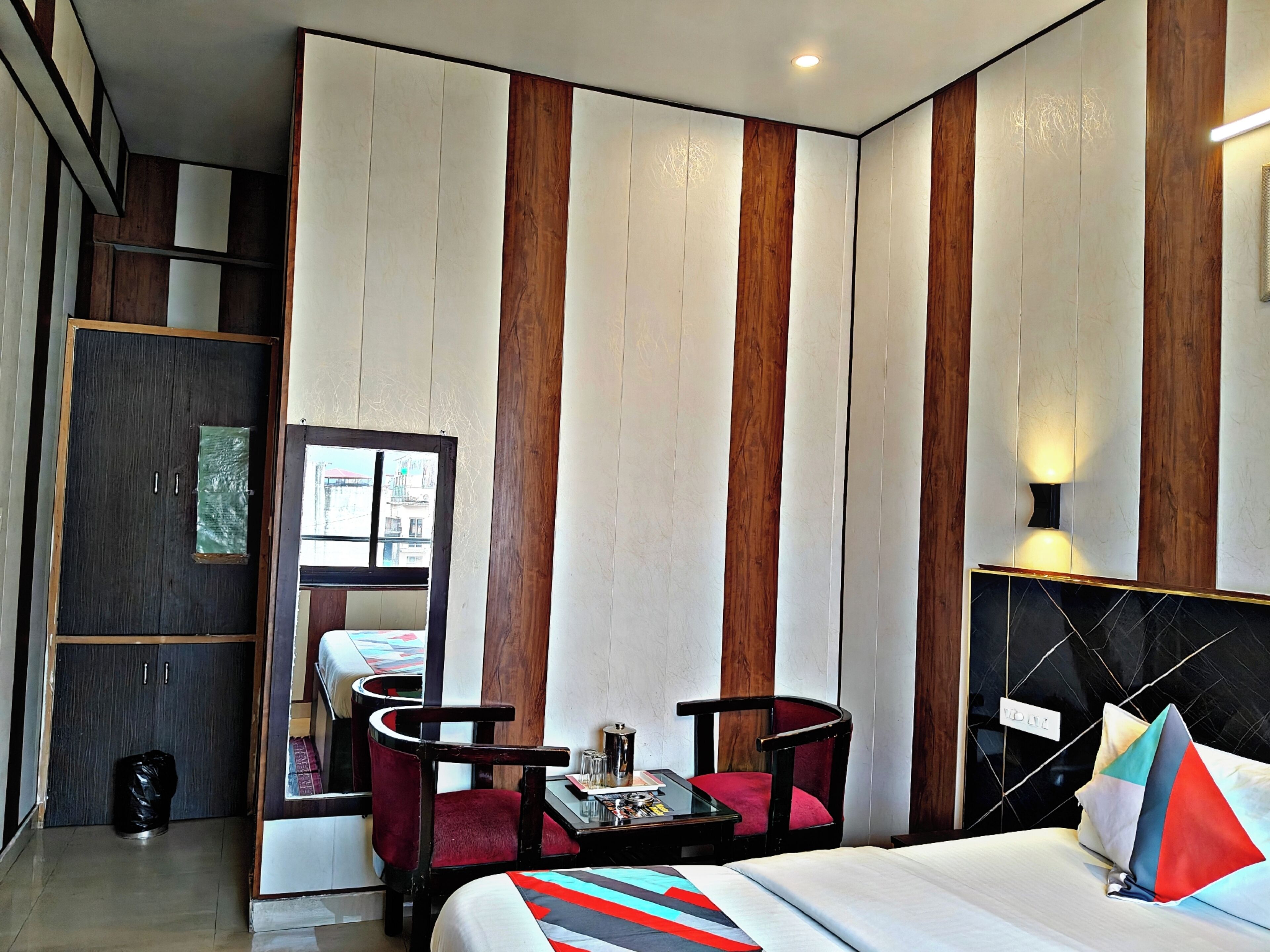Une chambre d’hôtel comprenant un lit, deux chaises, une petite table, un miroir et une armoire.