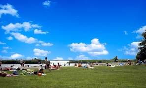 A grassy park with people sunbathing and swimming in the background. - 5-person Chalet La Casita by the Water With Parking Space (Anjum)