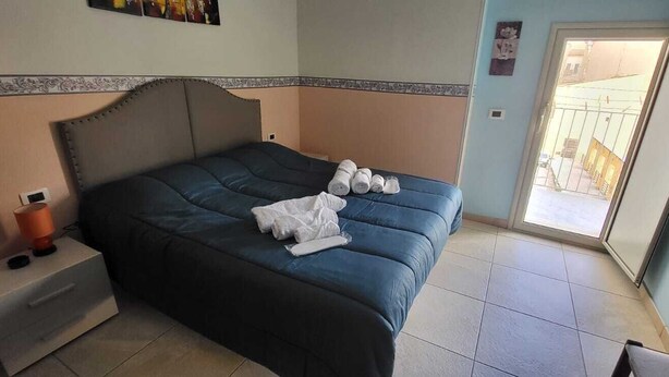 Een slaapkamer met een bed, nachtkastje, lamp en uitzicht.