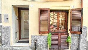 A building entrance with a door, a window with wooden shutters, and a small plant hanging on the wall. - Il Viandante, Loft Indipendente nel centro di Cagliari (Cagliari)