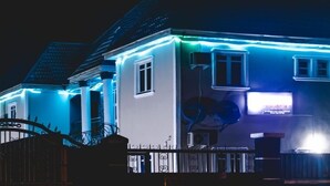 Una casa con fachada blanca e iluminación azul exterior.