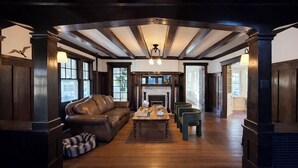 A spacious living room with a leather sofa, a wooden coffee table, and a fireplace. - Pet Friendly Estate, Sleeps 20 Includes Linens, Towels, Beach Tags & Parking (Ocean City)