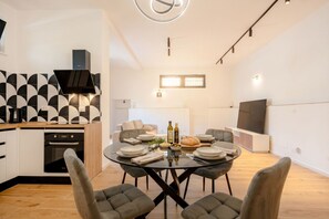 A modern kitchen with a dining area, a built-in oven, and a flat-screen TV. - MareVista Garden - Private Garde and Parking (Bari)